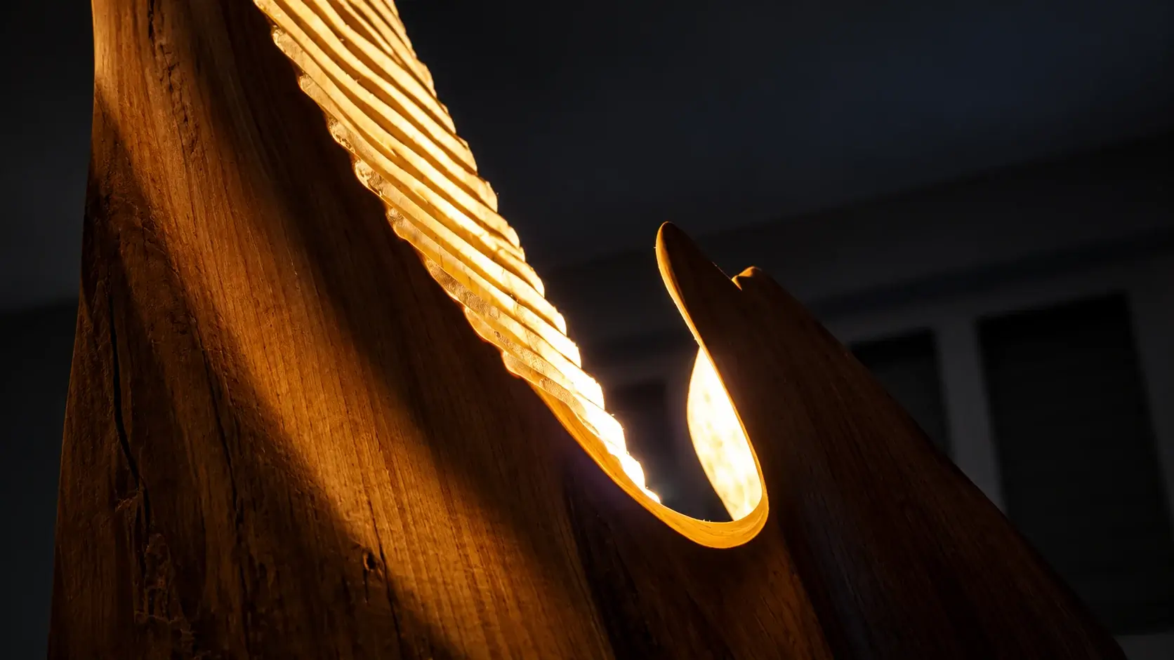 Dettaglio ravvicinato di una scultura RadiAnima in legno intagliato, con venature e incisioni illuminate da una luce calda.