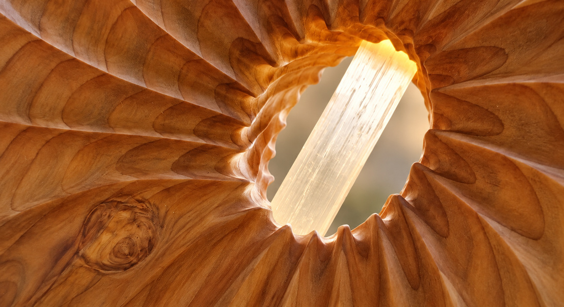 Dettaglio della selenite illuminata tra le venature del cedro scolpito.